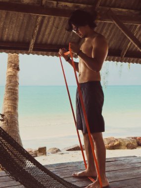 Deniz kenarındaki kulübede lastik bant ile egzersiz ve egzersiz. Asya 'da plaj rahatlığı..
