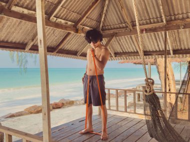 Deniz kenarındaki kulübede lastik bant ile egzersiz ve egzersiz. Asya 'da plaj rahatlığı..