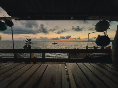 Altın saat boyunca okyanus ufkuna bakan fenerli ahşap güverte.