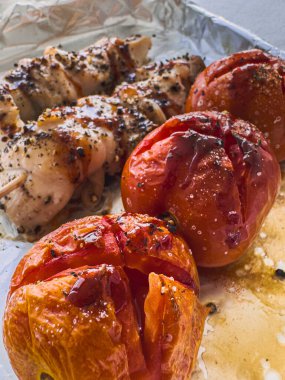 Kızarmış domatesli fırında tavuk folyo tepsisinde servis edilir.