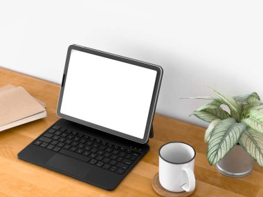 Laptop, tahta bir masanın üzerinde beyaz bir kupa ve saksı bitkisi ile açık. Laptop ekranı boş, ve masa kitaplarla dolu.