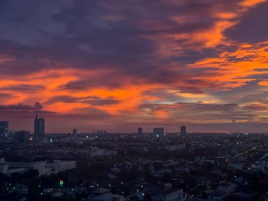 Nefes kesici bir günbatımı, canlı renkleri ve dramatik bulutlarıyla şehrin ufuk çizgisini muhteşem bir şekilde aydınlatıyor.