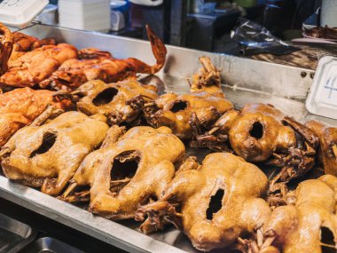 Kızarmış tavuklar canlı bir yerel markette güzel bir şekilde sergileniyor, çeşitli mutfak lezzetleri sergileniyor.