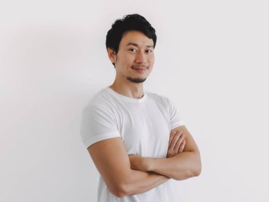 Taylandlı erkek, kollarını kavuşturmuş, kendine güveni tam, beyaz tişört giyiyor ve rahat görünüyor, Asyalı kökenli.