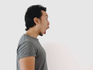 Geniş bir ağız ve açık bir ifade ile şaşırmış bir adam, düz bir arka plan karşı kenardan görülen