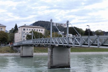 Salzburg, Avusturya - Ekim 12024: Modern Çelik Köprü Salzach Nehri boyunca uzanan tarihi mimari ve Hillside Sahnesi. Yüksek kalite fotoğraf