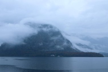 Serene Morning View of Misty Hallstatt Lake and Forested Hillside with Hidden Village, Capturing the Tranquility and Atmospheric Beauty of Austria s Iconic Alpine Landscape. High quality photo clipart