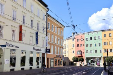 Innsbruck, Avusturya - 29 Eylül 2024: Tarihi Wagnersche kitapçısı, büyüleyici cepheleri, tramvay hatları, bisikletçileri ve Avusturya 'nın aydınlık gökyüzü altında yayalar olan Renkli Innsbruck Caddesi