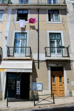 Lisbon, Portugal: August 17 2017: Traditional Lisbon Building with Tiled Facade, Restaurante Rio Coura, and Hanging Laundry in Portugal s Historic District. High quality photo clipart