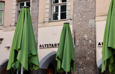 Altstadt Innsbruck Facade with Green Patio Umbrellas Closed Against Historic Stone Walls in Old Town. High quality photo clipart