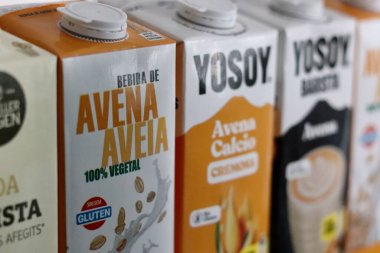 Tetra Pak kartonlarındaki çeşitli İspanyol yulaf sütlerinin yakın plan resmi bir mağaza rafına dizilmişti. Pakette Avena, bitkisel ve günah glüten gibi bitkisel bazlı etiketler yer alıyor.
