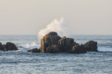 Gün batımında Britanya kıyılarındaki kayalara vuran dalgalar.