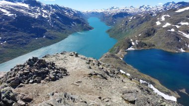 Norveç 'teki Jotunheimen Ulusal Parkı' ndaki Besseggen yürüyüş yolunun nefes kesici panoramik manzarası. Turkuaz gölü, dik yamaçları ve yaz güneşinin altında berrak mavi gökyüzü olan manzaralı bir dağ manzarası..