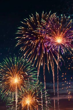 Gece gökyüzünü aydınlatan güzel havai fişeklerle donatılmış soyut bir arka plan. Bokeh etkisi