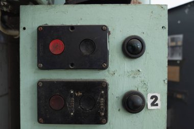 İki düğmesi ve metal plakası olan eski kontrol paneli. Üzerinde yazı olan kırmızı düğme dur ve siyah düğme ona endüstriyel ve klasik bir görünüm verir..