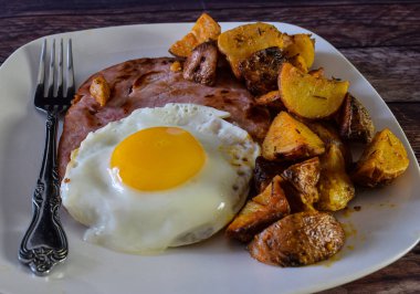 ham top with  a fried egg and home fries, 