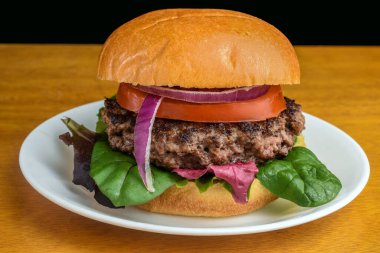 Karışık sebzeli hamburger ve üstüne de domates ve soğan.