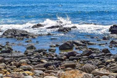 Dalgalar kıyıda kayalara çarpıyor.