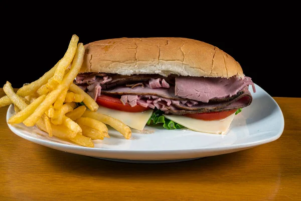 Stock image roast beef sub with tomato lettuce and  cheese served with fries