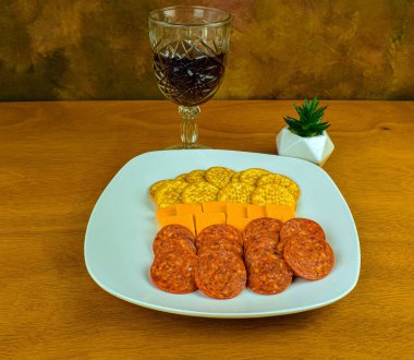 Kraker, peynir ve pepperoniden oluşan bir aperatif tabağı.