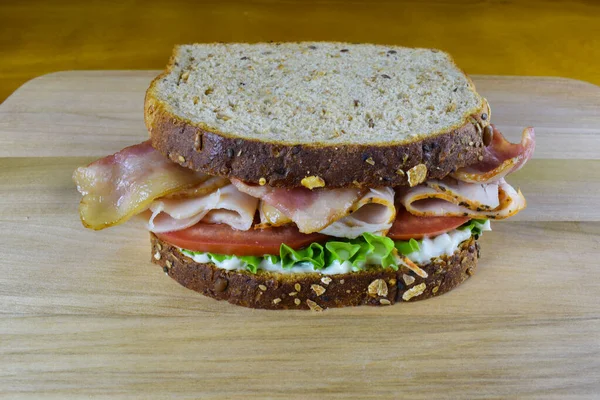turkey bacon sandwich consisting  of bacon,turkey meat, tomatoes between wheat bread.
