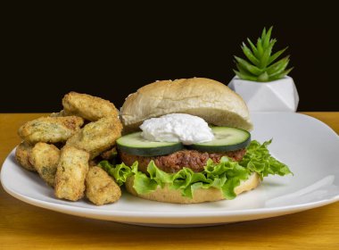 Salatalık ve brokoli ile servis edilen süzme peynirli bitkisel burger üstü.,