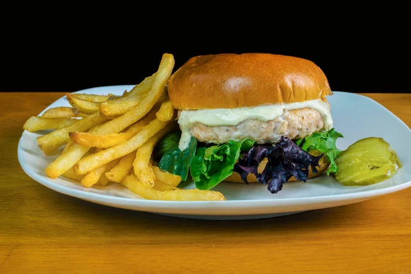 salmon burger top with tarter sauce and served with fries