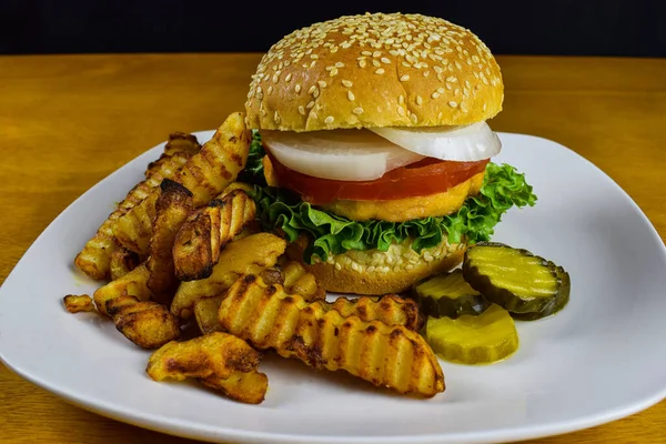 salmon burger with fries and pickles,