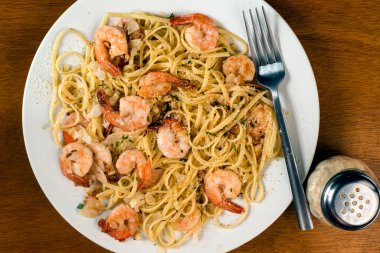 Linguine sotelenmiş karides, maydanoz ve parmesan peyniri ile servis edilir.,