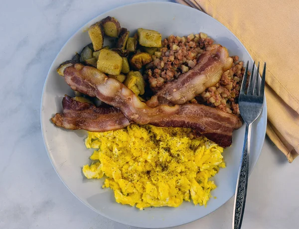 早餐盘 上面有炒鸡蛋和黑胡椒 还有熏肉 家庭薯条和玉米牛肉杂烩 — 图库照片