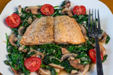 Fırında somon balığı sotelenmiş ıspanak ve mantarla servis edilir.