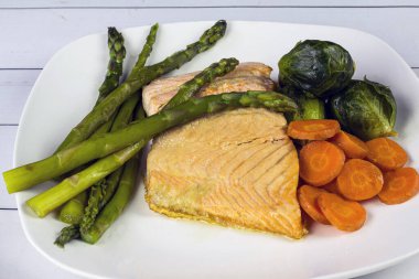 Kuşkonmaz, havuç ve brussel filizleriyle servis edilmiş fırında somon.