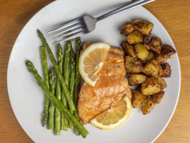 Limonlu ballı somon balığı üstü ve sotelenmiş kuşkonmazla servis edilir.