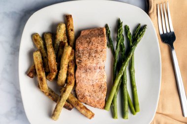 Brokoli kızartması ve kuşkonmazla servis edilen mevsim pişmiş somon balığı.