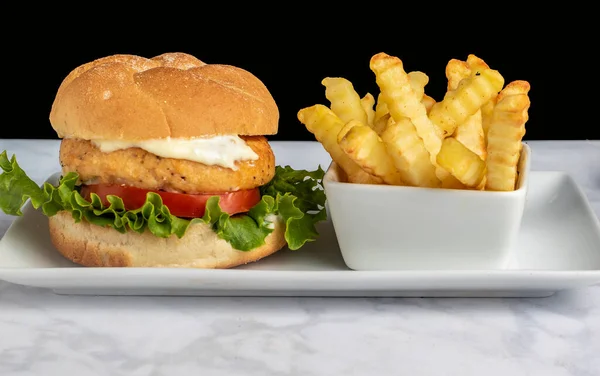 salmon burger on a bulkie roll served with fries,
