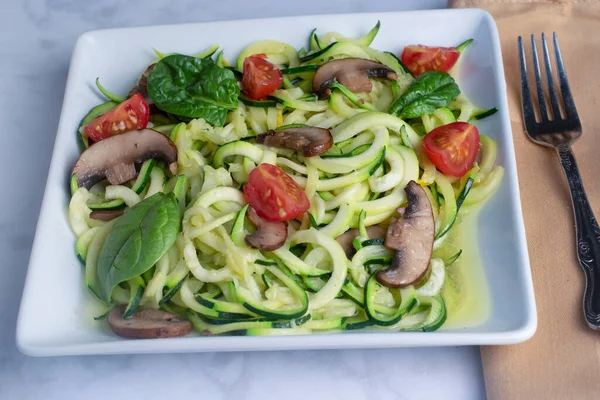 stock image zucchini noodles served with  sauteed mushrooms , tomatoes  and spinach, 