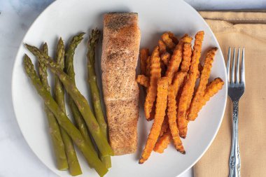 Kuşkonmaz ve patates kızartmasıyla servis edilen somon filetosu.