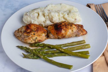 Patates püresi ve kuşkonmazla servis edilen tavuk butları., 