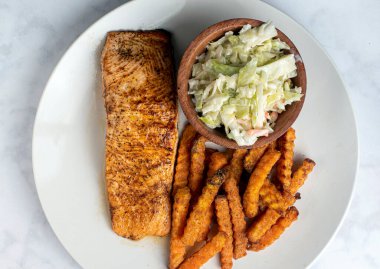 Fırında somon, lahana salatası ve patates kızartmasıyla servis edilir.