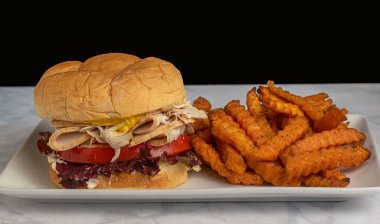 Tatlı patates kızartmasıyla servis edilen hindili sandviç.