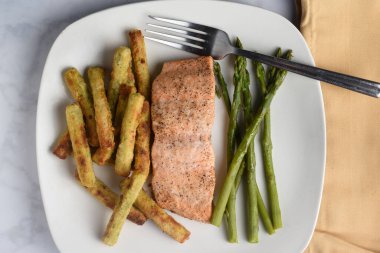 Brokoli kızartması ve kuşkonmazla servis edilen mevsim pişmiş somon balığı.