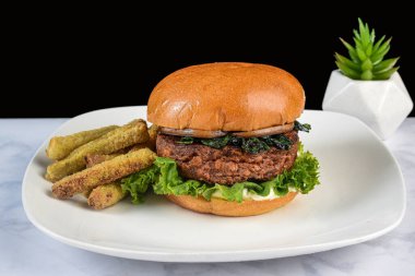 Sebzeli burger üstü sotelenmiş ıspanak ve brokoli kızartmasıyla servis edilen mantarlar.