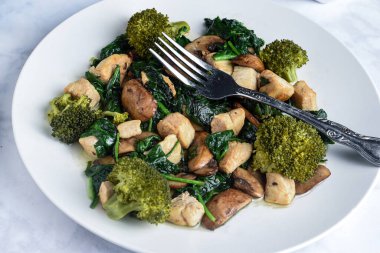 Sote ıspanak, mantar ve brokoli ile servis edilen tavuk., 