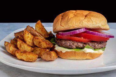 Sulu hamburger üstü domatesli ve soğanlı patates dilimli.