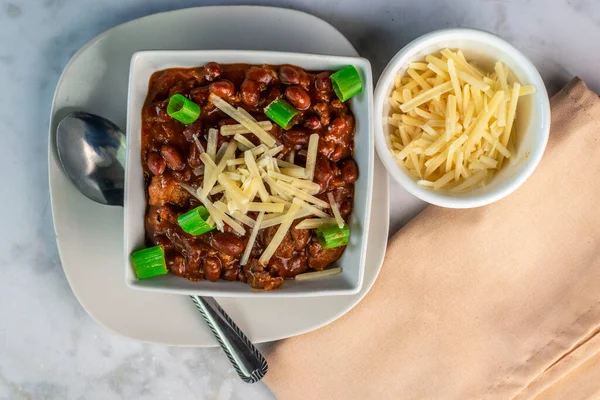 chili  in a bowl  top with cheese and green onions