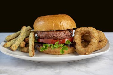 Brokoli kızartması ve karnabahar soğan halkalarıyla servis edilen brioche ekmeğine dayalı hamburger.