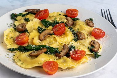 İtalyan sosisli ravioli, üstü sotelenmiş ıspanak, mantar ve domates.,