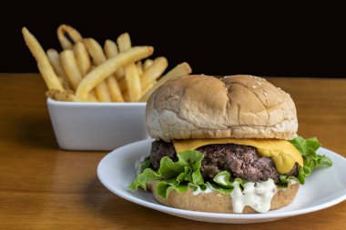 Peynirli burger üstü hardallı susamlı ekmek ve patates kızartması.   