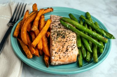 Mevsimlik somon, sotelenmiş yeşil fasulye ve patates kızartması ile servis edilir.,