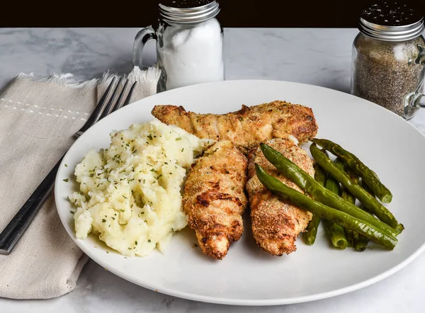 Sotelenmiş yeşil fasulyeyle servis edilen tavuk konserveleri ve pastili patates püresi.,